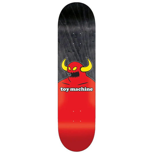Skateboard deck with a red and black design featuring a cartoonish devil face and 'toy machine' text on a white background.