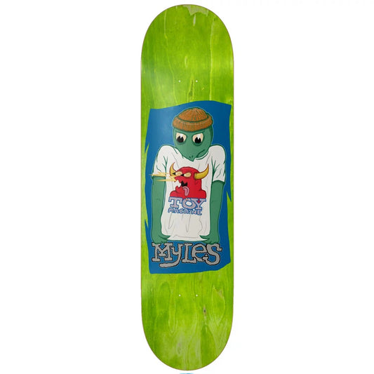 A skateboard deck with a bright green wood-grain finish, featuring a large graphic in the center. The graphic shows a green cartoon turtle wearing a brown beanie and a white t-shirt with a red bull logo, set against a blue background with the text 'MYLES' at the bottom.