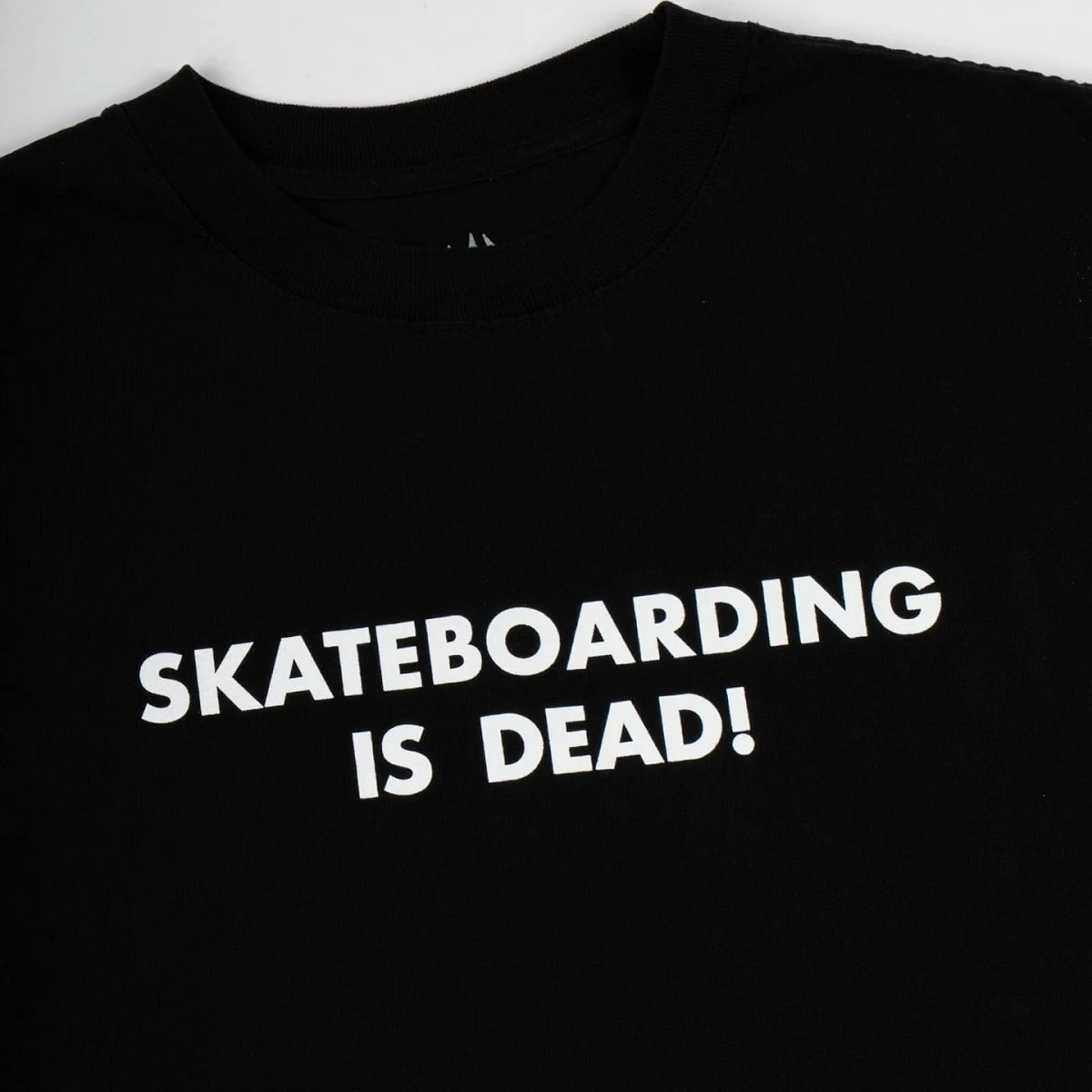 A close-up of a black crewneck t-shirt featuring the slogan 'SKATEBOARDING IS DEAD!' printed in bold white capital letters across the chest.