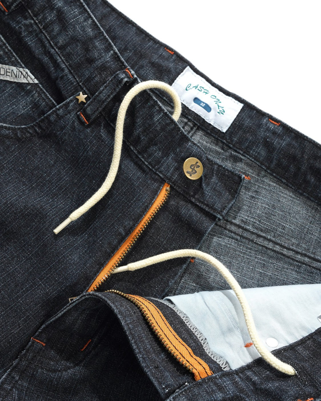 Close-up of dark blue denim jeans with a brand label and button.