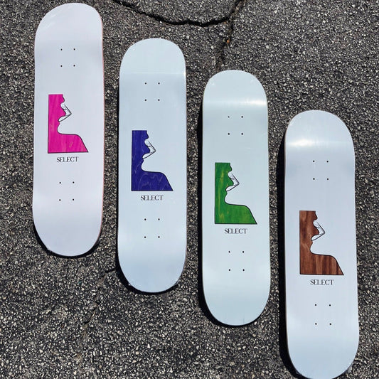 Four skateboard decks with colorful graphics on a textured surface